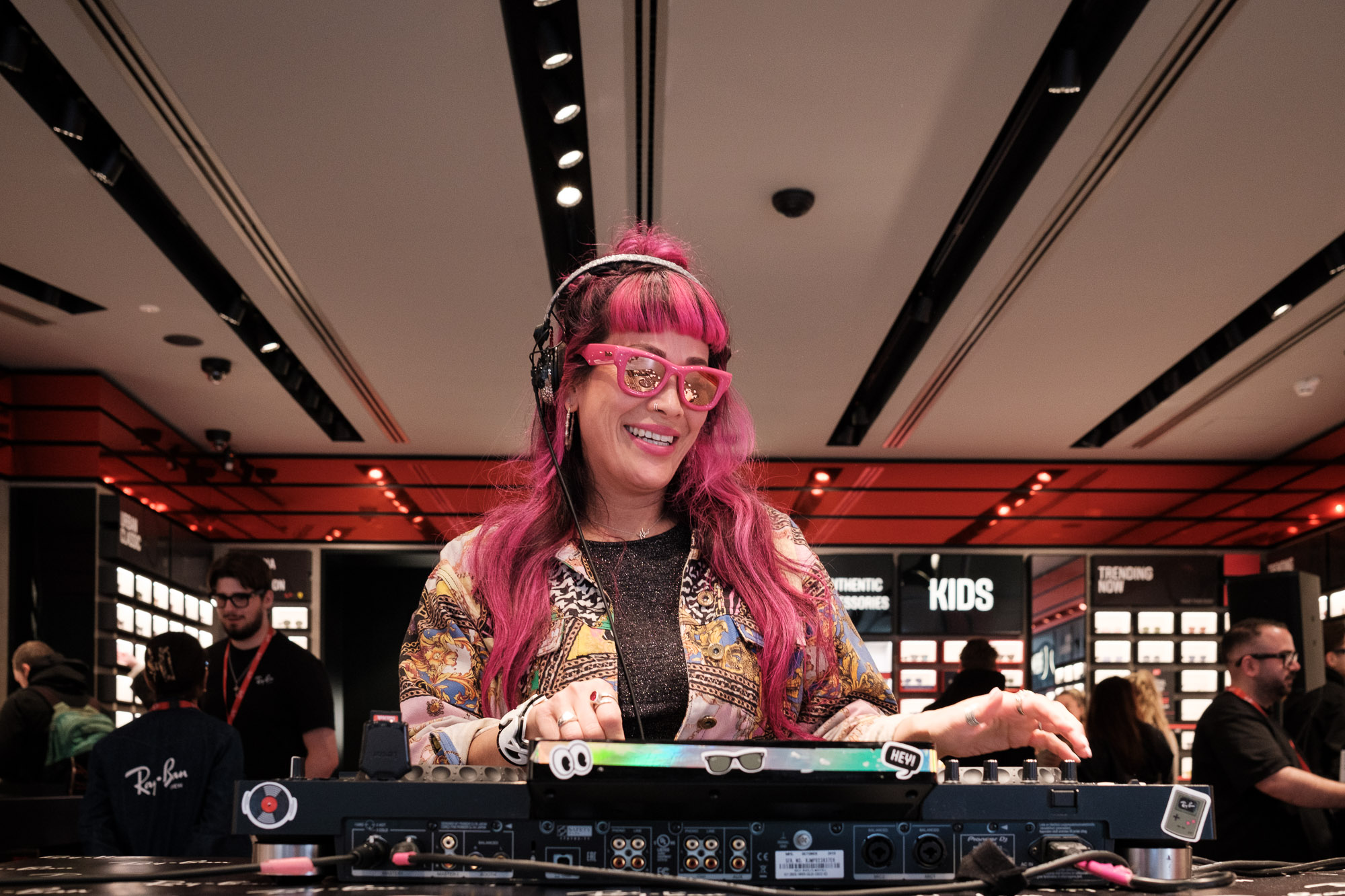 Dj met roze haar en roze bril achter haar mengpaneel
