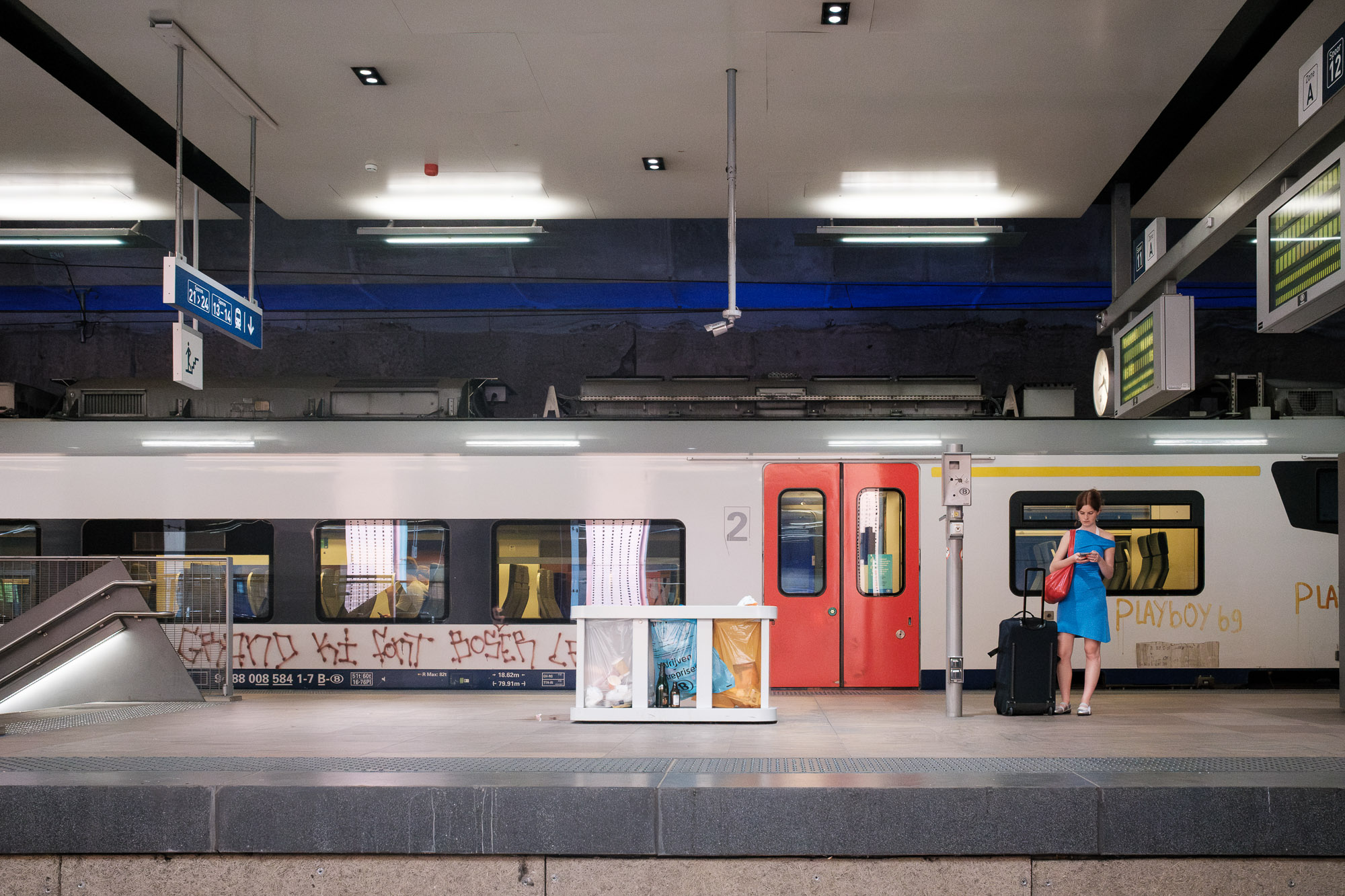 Vrouw in blauwe jurk wacht op de trein in Antwerpen