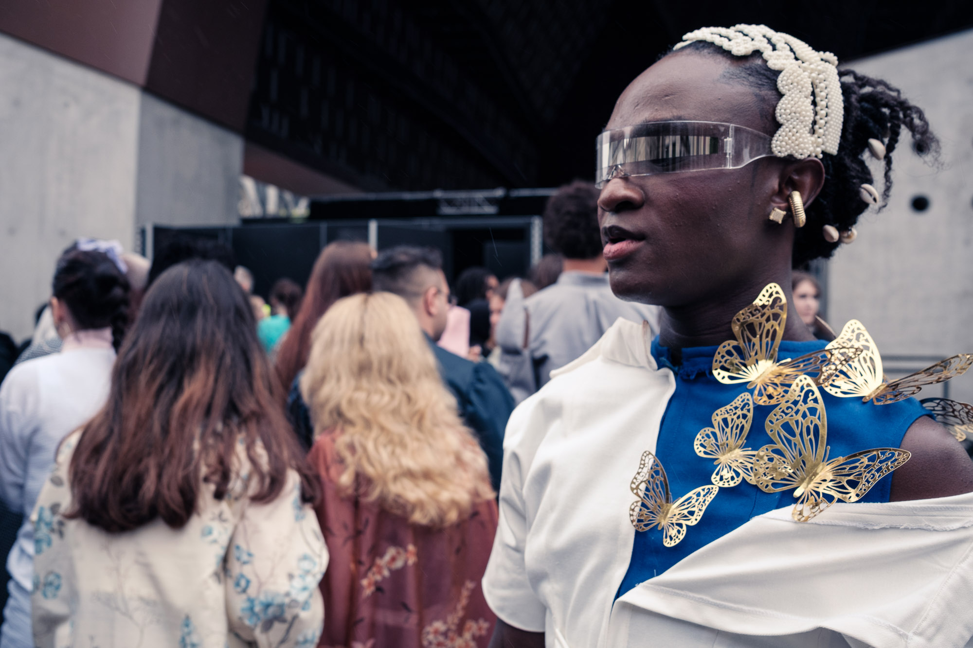 Vrouw met gouden vlinders en perlen haarband in de rij voor een modeshow