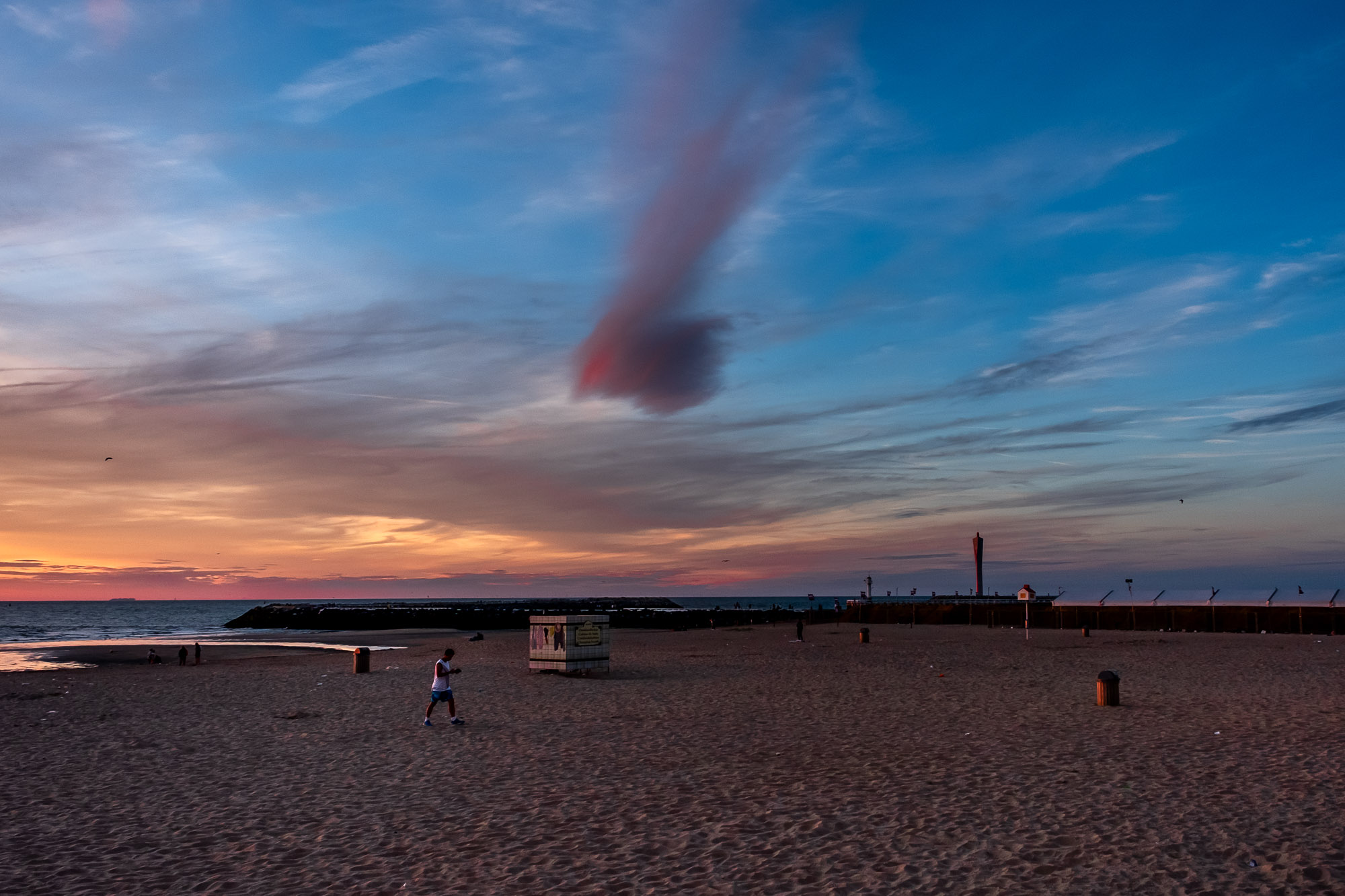 Man op de golfbreker onder een zware wolkenhemel in Oostende